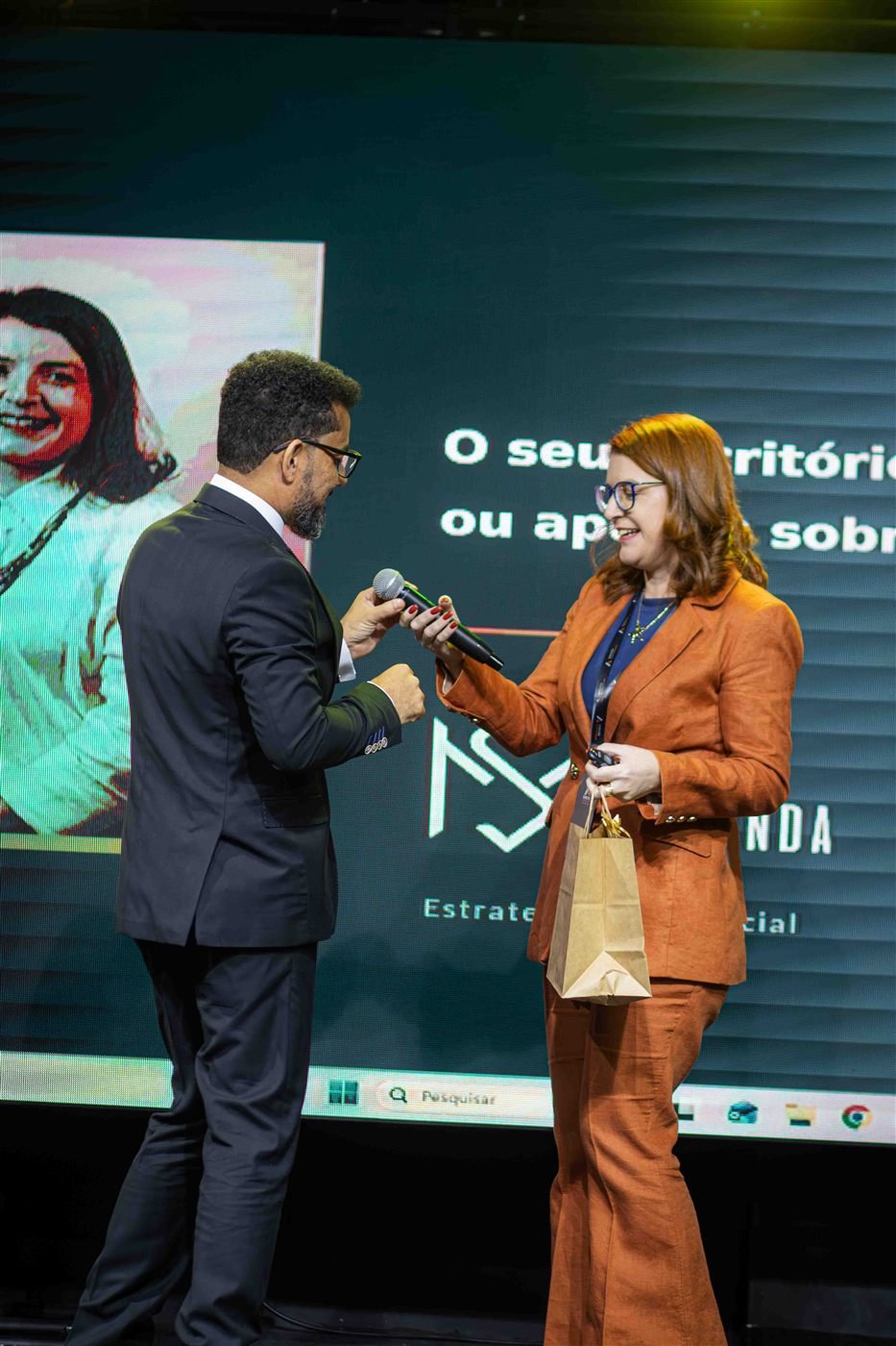 Silvia Miranda no palco sendo entrevistada, com seu nome e 