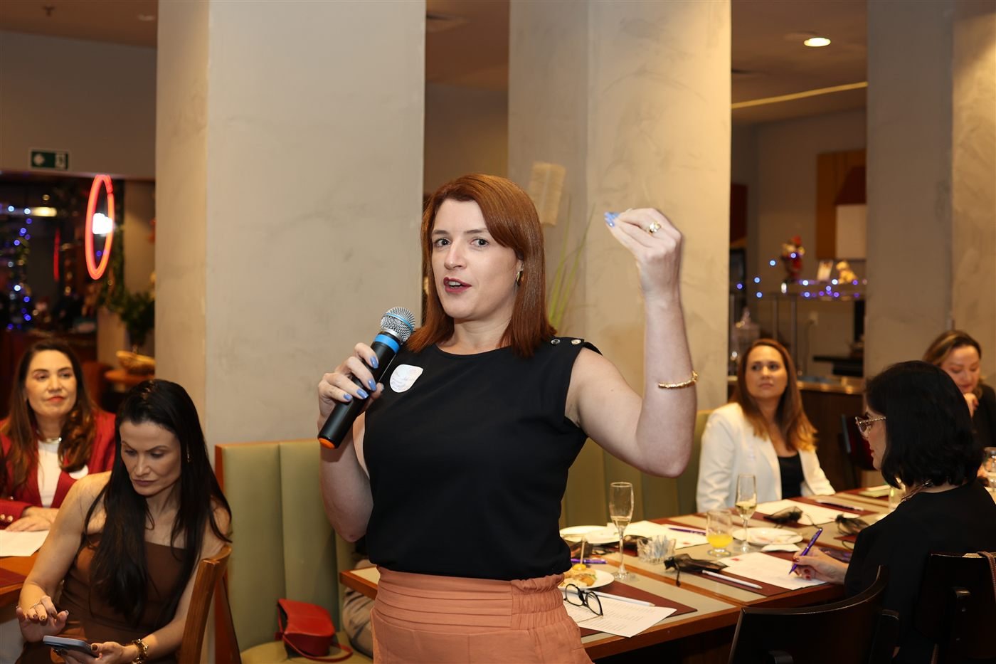 Silvia Miranda falando ao microfone em evento de networking